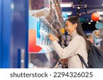 Small photo of Happy Asian woman handle a doll from gashapon capsule toy vending machine while shopping at Tokyo city, Japan. Attractive girl enjoy and fun outdoor travel city street on autumn holiday vacation.