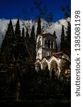 Small photo of Greek church with bell tower surrounded by trees in Athens, Greece. Deep, blue sky with white clouds in the background.