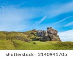 Small photo of in early morning,spring sunlight,a large bare rock sitting on a grassy steep slope of Caer Caaradoc hillside,incongruous in the foreground.