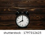 Small photo of Clock on a wooden background. The clock shows the time of eight o'clock in the afternoon. The clock shows the time of eight o'clock in the morning. An image of a retro clock showing 08:00 pm/am