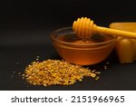 Small photo of A ladle of honey on the background of a honeycomb of a bee. Honey tidbit in a glass jar honey spoon, bee bread and a honeycomb of wax on a black background. Healthy food concept.