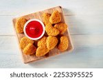 Small photo of Chicken nuggets with bbq sauce on a rustic wooden background, top shot. A crispy appetizer at a restaurant, finger food