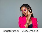 Fashion Portrait Black Woman in Pink stylish jacket. Pink Makeup curly hair and braids. Luxury Fashion model African American posing in studio against a pink wall. Beautiful black   woman    