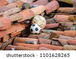 two soccer balls stacked or trapped on the roof of a house
