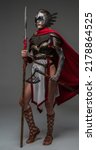 Small photo of Studio shot of attractive woman warrior dressed in ancient armor holding axe and spear.