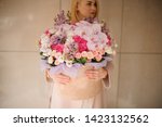 Small photo of Girl holding a huge spring box of tender multicolored pink flowers decorated with green leaves