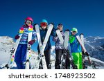 Ski vacation portrait many children stand with sport equipment in hands lean to camera wearing color google and helmets