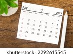 July 2023 Monthly calendar for 2023 year with pen on wooden background.