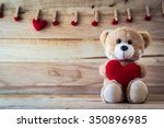 Teddy bear holding a heart-shaped pillow with plank wood board background