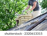 Small photo of Bricklayer repair brick chimney on asbestos house rooftop