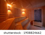 Seat in sauna room. Empty wooden steam room with stone heater.Sauna room for good health. Sauna room with traditional sauna accessories.Healthy and spa life style.