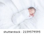 a newborn baby swaddled wrapped in white cloth sleeping on a white fluffy blanket
