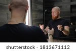 Small photo of A young, Caucasian, charismatic, bald guy with a red beard dances and sings in front of the mirror, talking to his reflection in a modern bathroom. Energize for the day.