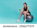 Asian beautiful happy woman holding water bottle and sitting on fit ball after exercise isolated on blue color background.Concept of slim and healthy girl workout.