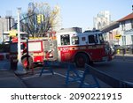 Small photo of Brooklyn, NY, USA - Dec 13, 2021: Fire engine turning onto Old Fulton Street along the Brooklyn waterfront with Manhattan skyline in background