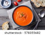 Tomato soup in a black bowl on wooden background. Top view. Copy space