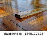 Small photo of A piece of parquet floor tile slab sticking out after being stepped on as the wooden strip has become unglued and loose due to wear and tear over time.