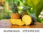 Group of sliced and half of pineapple(Ananas comosus) on wooden table with blurred garden background.Sweet,sour and juicy taste.Have a lot of fiber,vitamins C and minerals.Fruits or healthcare concept