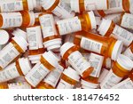 Dozens of prescription medicine bottles in a jumble. This collection of pill bottles is symbolic of the many medications senior adults and chronically ill people take. 