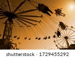 Silhouette of people riding carnival swing ride at sunset