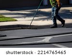 Small photo of Worker using a sealcoating brush during asphalt resurfacing project