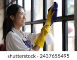 Person cleaning the room, cleaning staff is using cloth and spraying disinfectant to wipe the glass in the company office room. Cleaning staff. Maintaining cleanliness.