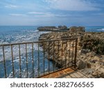 Small photo of View from the pier through the rusty bridge fence with an old rusty lock over the Mediterranean sea and rocks on a sunny day in Aye Napa, Cyprus.