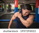 A fit man experiences rotator cuff tear, sprain or injury during a workout session at the gym.