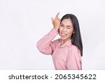 Small photo of A young woman taunting by making a loser gesture while sticking her tongue out. Possibly lighthearted banter.