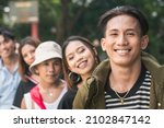 Small photo of Five friends posing and smiling while in a single file. Focused on the young man on the right.