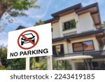 A no parking sign in front of a gated house. A warning prohibiting vehicles blocking the gate or the side of the road.