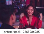 Small photo of A bubbly young woman flips her hair as she flirts with the man she is interested with. Man and woman having fun on the first date. Beautiful lady shows her charm with a hair flip.