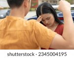 Small photo of A woman looks down ashamed after being berated by her toxic boyfriend. A controlling and emotionally abusive man insulting his partner at the parking lot. An inequitable and toxic relationship.