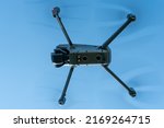 Small photo of A modern drone against a clear blue sky. The quadcopter hovered motionless in the sky. The use of aircraft for reconnaissance and fire correction.