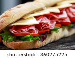 Sandwich with lettuce, slices of fresh tomatoes, salami, hum and cheese