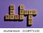 Small photo of Abbreviations and acronyms, including ROFL, FYI, IRL, HMB and RBTL in crossword form isolated on purple background