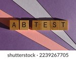 Small photo of A B Test, also known as split testing in business whereby an audience is divided into two groups, in wooden alphabet letters isolated on background as banner headline