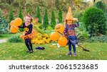 Small photo of Little witches learn to fly broomsticks at an outdoor Halloween party. Happy children in carnival costumes with balloons have fun and play witches in the fall season. Kids play witches on broomsticks.