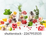 Refreshing drinks with ice cubes with fruits and citrus fruits, ice with blackberries and raspberries, gooseberries and currants, with mint, a jug of water and citrus fruits