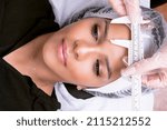 Small photo of Unidentified beautician in gloves and gown measures the proportions of the eyebrows. Microblading and beauty industry concept
