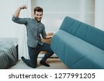 Small photo of Young Male Moves A Big Sofa In The New Apartment. Reshuffle In The Room Concept. Domestic Problems. Clean Residence. Powerful Man. Try Hard. Power Showing. Changes In The Living Room.