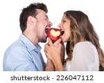 Happiness, health and love concept. Smiling couple with apple heart, isolated on white background