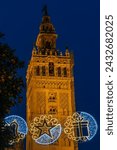Small photo of Seville, Spain 01-06-2024 The tower of the Giralda Cathedral in the centre of the Seville during blue hour and sunrise, with the iconic orange fruit trees and the ornaments on the facade of the church