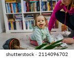 Small photo of one caucasian baby girl making mess playing and mischief with bad behavior ripping paper towel and flower pot crushed on the floor naughty kid at home childhood and growing up misbehavior concept