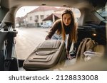 Small photo of One young beautiful woman student travel concept female take luggage baggage suitcase and other stuff and belongings from the back of her car while moving into dormitory on college campus real people