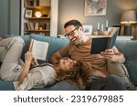 Small photo of Adult couple man and woman Caucasian husband and wife in a relationship real book hold books on the sofa bed at home in the apartment reading leisure bonding family concept real people copy space