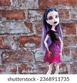 Small photo of Randburg, South Africa: 09-25-2023: Pensive purple-haired doll, posed offset against a red brick background. Monster High Spectra Vondergeist. Space for copy. Shallow depth of field.