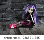 Small photo of Randburg, South Africa: 09-25-2023: Pretty ghostly doll posed relaxing against a dark stone background. Monster High Spectra Vondergeist. Halloween. Shallow depth of field.