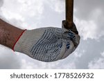 Small photo of a hand in a working glove holds a nail a hammer is brought over it for a blow bottom view
