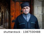 Small photo of Baku, Azerbaijan - April 15, 2017: Handsome elderly man smiles in national Azeri costume, hat and gray mustache